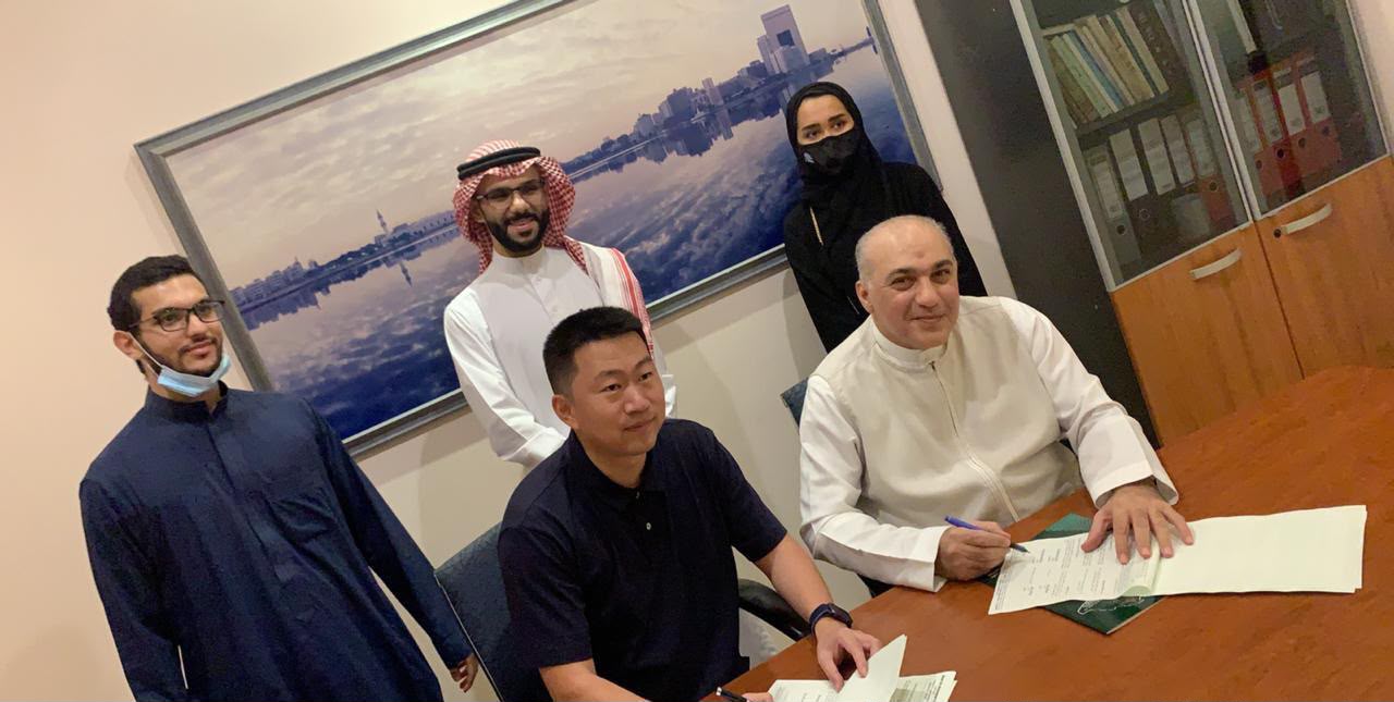 Mazin Kurdi signing an agreement with Andy, Director General of a Chinese company, in an office.