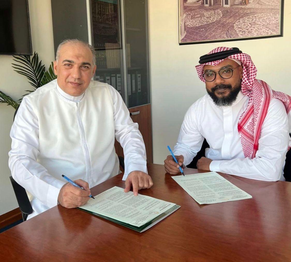 Mazin Kurdi signing an agreement with a colleague.